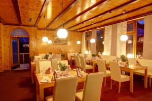 a dining room with tables and white chairs at Hotel-Restaurant Sonnenhof in Veitsrodt