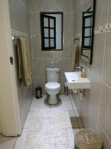 y baño con aseo, lavabo y espejo. en Pongola Road Self Catering Accommodation, en Uitenhage