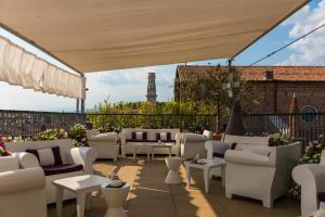 eine Terrasse mit weißen Stühlen und einem Leuchtturm im Hintergrund in der Unterkunft Due Torri Hotel in Verona