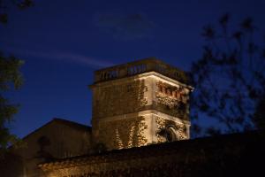 una torre de reloj en la parte superior de un edificio por la noche en Domaine Sainte Suzanne, en Puimisson