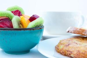 un bol azul de fruta junto a un plato de comida en Casa Maravilla en Faro de Peñas