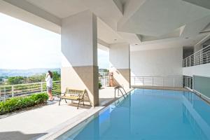 a woman standing on the balcony of a house with a swimming pool at Prima at Primavera Residences in Cagayan de Oro