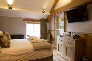a bedroom with a large bed with a flat screen tv at The Queen's Head Hotel in Troutbeck