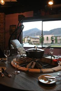a table with a pan on top of a table with wine glasses at Yadoya Lodge in Kyoto