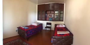 Habitación con 2 camas y una silla. en Shaki Host House en Sheki