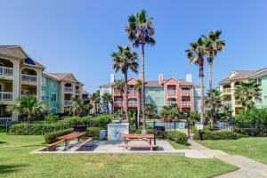 a park with benches and palm trees in front of condos at The Dawn Condominiums in Galveston
