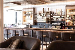 a bar with brown leather chairs and a counter at Aktiv- und Wellnesshotel Traube- Post in Curon Venosta