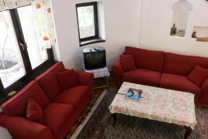 una sala de estar con 2 sofás rojos y una mesa. en Villa San, en Blagaj