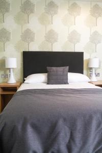 a bedroom with a large bed with two lamps at Hinxton Hall Conference Centre in Hinxton