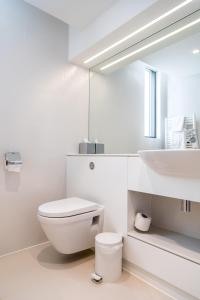 a white bathroom with a toilet and a sink at Hinxton Hall Conference Centre in Hinxton