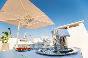 a table with an umbrella and wine glasses on it at Dimora Maio in Monopoli