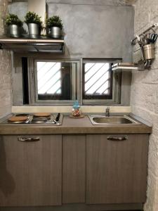 uma cozinha com um lavatório e duas janelas em L'Orecchietta em Ruvo di Puglia