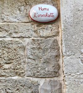 a sign on the side of a stone wall at L'Orecchietta in Ruvo di Puglia