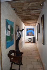 a hallway with paintings on the wall and a chair at Hermitage St Roch in Arc-en-Barrois