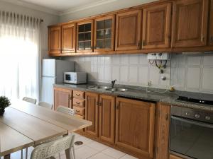 a kitchen with wooden cabinets and a sink and a table at Casa de Lencastre in Viana do Castelo