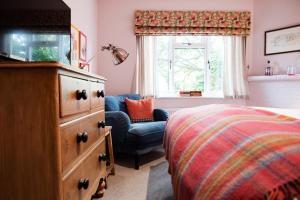 1 dormitorio con vestidor, cama y silla en Bel and The Dragon-Cookham en Cookham