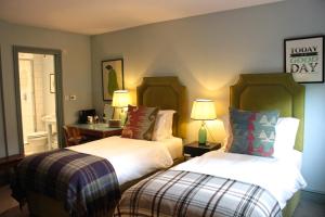 a bedroom with two beds and a table and a desk at Bel and The Dragon-Cookham in Cookham