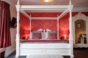 ein Schlafzimmer mit einem weißen Himmelbett mit roten Wänden in der Unterkunft The Bull Hotel in Bridport