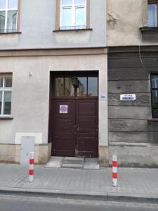 brązowe drzwi na budynku z dwoma pomarańczowymi i białymi biegunami w obiekcie Chodkiewicza 10 (A) - cozy studio by Homeprime w Krakowie