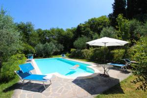 a swimming pool with two chairs and an umbrella at Villa Gioiosa in Monte San Savino