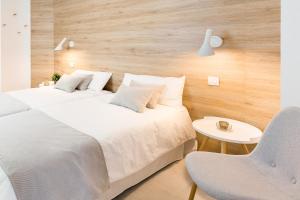 2 witte bedden in een kamer met een stoel bij Plaza de La Feria Premium Apartments in Las Palmas de Gran Canaria