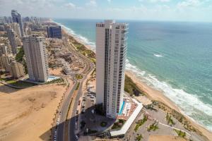 a tall building on the beach next to the ocean at Island Luxurious Suites Hotel and Spa- By Saida Hotels in Netanya