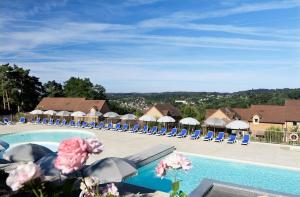 a resort with a pool with chairs and umbrellas at Résidence Odalys - Les Coteaux de Sarlat in Sarlat-la-Canéda