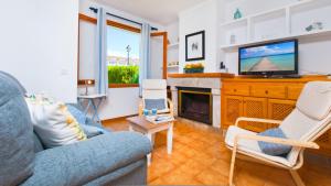 a living room with a blue couch and a tv at Casa GAVINES Alcudia in Playa de Muro