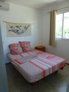 1 dormitorio con 1 cama con manta a rayas y ventana en Farehani 2 en Avatoru