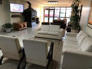 a living room with white couches and a tv at Center Hotel Cambará in Cambara do Sul