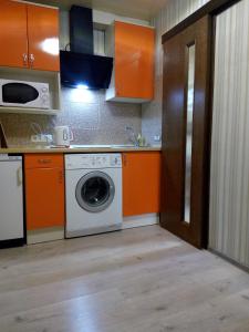リヴィウにあるVIP Квартираのキッチン(オレンジ色のキャビネット、洗濯機付)