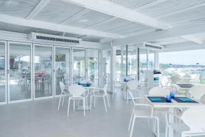 a white room with white chairs and tables and windows at FERGUS Style Carema Beach in Cala en Bosc