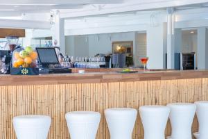 a row of white stools in front of a bar at FERGUS Style Carema Beach in Cala en Bosc