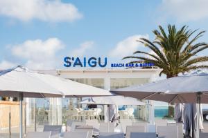 a beach with chairs and umbrellas and a hotel at FERGUS Style Carema Beach in Cala en Bosc