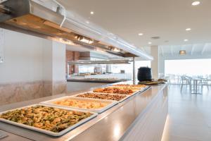 a buffet line with many trays of food at FERGUS Style Carema Beach in Cala en Bosc