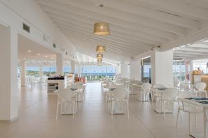 a dining room with white tables and chairs and windows at FERGUS Style Carema Beach in Cala en Bosc