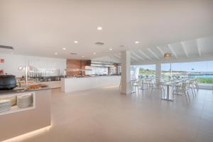 a large kitchen with tables and chairs and a counter at FERGUS Style Carema Beach in Cala en Bosc