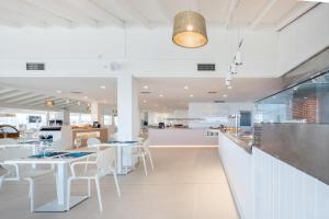 a dining room with white tables and white chairs at FERGUS Style Carema Beach in Cala en Bosc