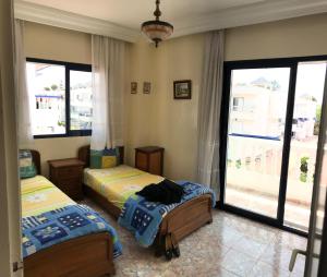 een slaapkamer met 2 bedden en een groot raam bij Appartement Palm Beach in Mohammedia