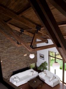 a living room with two white couches and wooden ceilings at The Reddoorshouse in Solishta