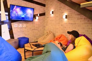 a woman sitting on a couch watching a tv at Music Hostel in Poltava