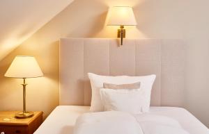 a bedroom with a white bed with two lamps at Hotel Freisinger Hof in Munich