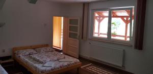 a bedroom with a bed and a window and a door at Korondi Pisztrangos in Corund