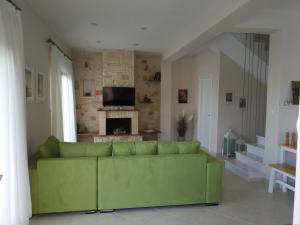 a green couch in a living room with a fireplace at #Luxlikehome - Villa Vista al Mar in Paliouri