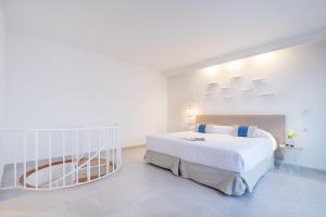a white bedroom with a large bed and a table at FERGUS Style Carema Beach in Cala en Bosc