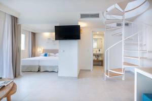 a white bedroom with a bed and a spiral staircase at FERGUS Style Carema Beach in Cala en Bosc