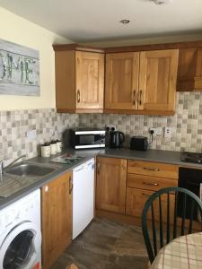 a kitchen with wooden cabinets and a white dishwasher at Old Mill Cottage in Swinford