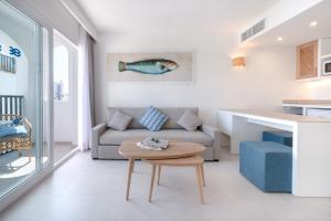 a living room with a couch and a table at FERGUS Style Carema Beach in Cala en Bosc