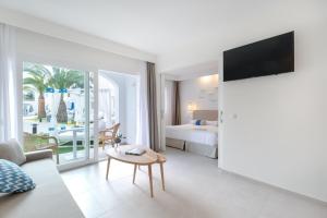 a hotel room with a bed and a living room at FERGUS Style Carema Beach in Cala en Bosc