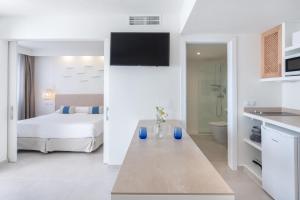 a white room with a bed and a bathroom at FERGUS Style Carema Beach in Cala en Bosc